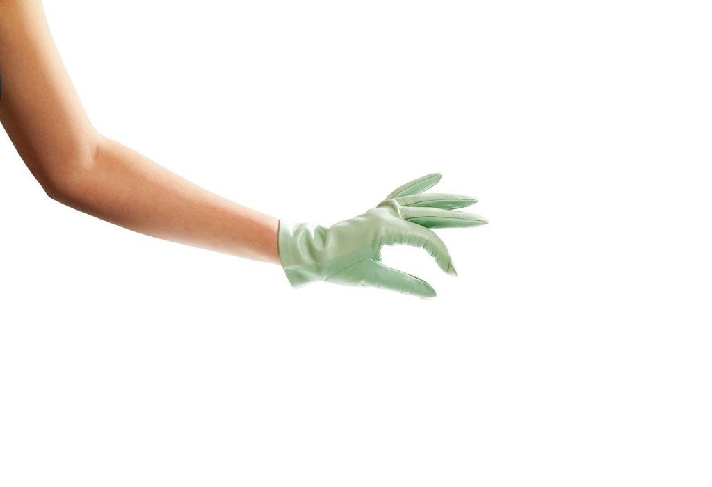 A person wearing a shiny red glove on their left hand, posed against a bright background. The arm is relaxed, and the person is dressed in dark clothing, emphasizing the vivid color of the glove.